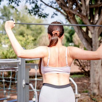 Frau trainiert mit Gummiband, Ansicht von hinten